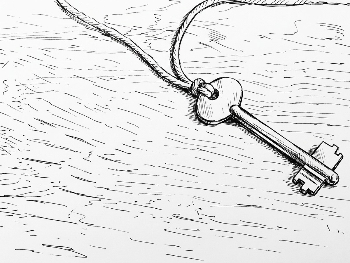 A single old key on a cord, lying on a wooden table.